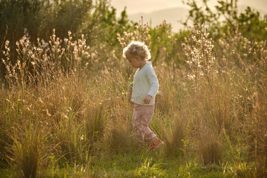 Cute girl with basket walking on grassy lush meadow
