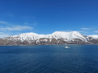 Fototapeta na wymiar Serene Winter Landscape: Majestic Mountains, Pristine Snow, and Tranquil Sea a view from svalbard and jan mayen norway