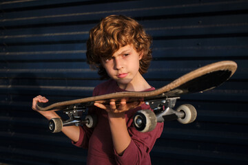 Fototapeta na wymiar Boy examining skateboard against blue wall