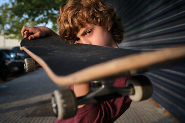 Serious little skater inspecting skateboard