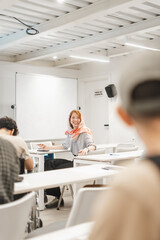 Happy, overjoyed, muslim female employee listening to her coworker joking at the middle of the meeting. Businesswoman wearing hijab smiling