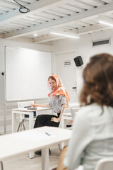 Obraz premium Female redhead employee wearing hijab looking at something during presentation and smiling