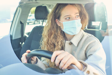 Crop woman in face mask driving modern car in city