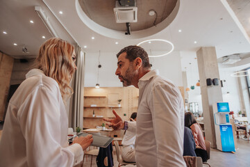 Businessman gesticulating with hand while explaining something to his female blonde partner, they...
