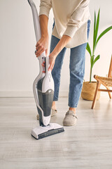 Anonymous woman removing container from modern upright vacuum cleaner