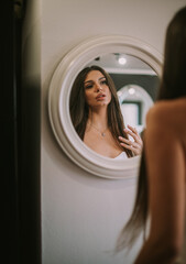 Fototapeta premium Brunette woman looking at herself in a mirror after hairdressing at the salon 