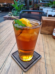 A glass of iced peach tea at the top of a wooden table