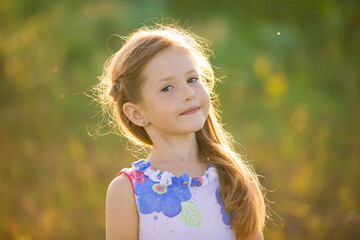 Close-up portrait of a charming blonde girl in the rays of the setting sun.