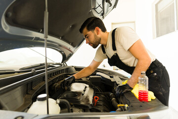 Fototapeta na wymiar Worker cleaning and polishing car engine at the auto detail service