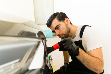 Young worker cleaning the car grille at auto detail service