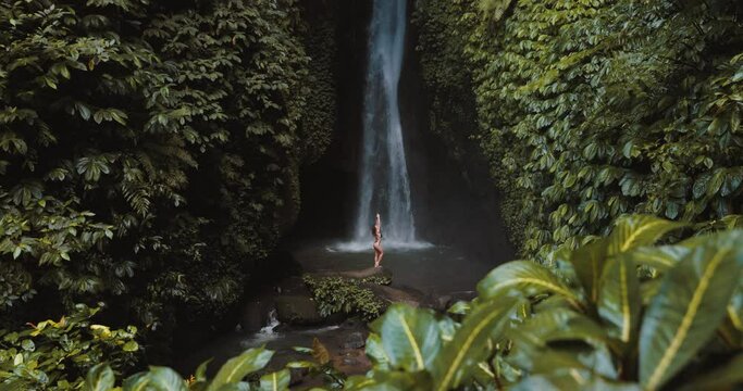Popular waterfall and woman in bikini. Traveler girl posing on waterfall