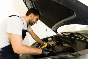 Car mechanic checking the voltage of battery using voltmeter at garage