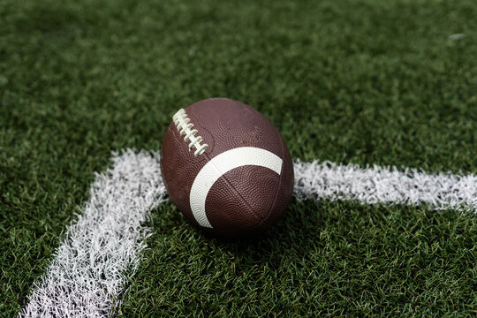 Close up view of an American Football sitting on a grass football field on the yard line. Generic Sports image 