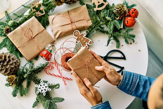 Faceless person putting present wrapped in paper on Christmas table