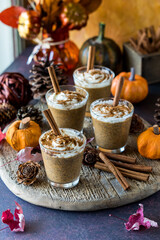 A vertical view of pumpkin spice chia puddings surrounded by autumn decorations.