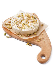 Wooden board of tasty Tahini halva with pistachios on white background