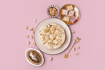 Plate of tasty Tahini halva with pistachios and turkish delight on pink background
