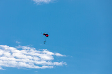 Naklejka na ściany i meble Parachute in the sky. Skydiver is flying a parachute in the blue sky