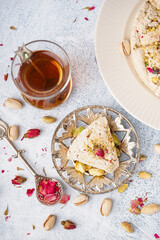 Plates with tasty Tahini halva and glass of Turkish tea on light background