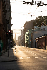 Rising sun and church t the end of an almost empty street in city at 5am.