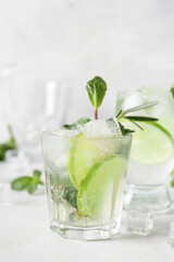 Glass of tasty mojito on light background