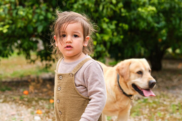 Cute girl with Labrador Retriever in garden