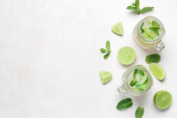 Mason jars of tasty mojito and ingredients on light background