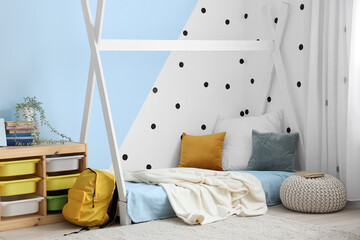 Interior of children's bedroom with cozy bed, shelving unit and pouf