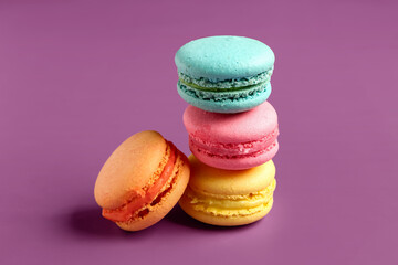 Different tasty sweet macaroons on purple background