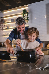 Ethnic father and son cooking in kitchen together