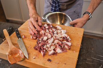 Crop man adding cut octopus into bowl