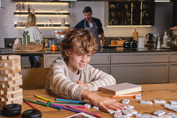 Boy playing domino in kitchen against parents