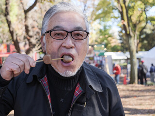 An asian man in glasses eating dango - 629245064
