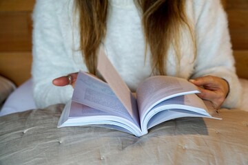 Close up view of a woman reading a book in bed