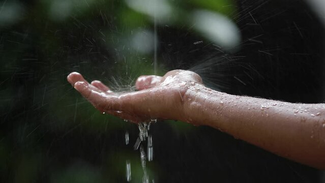 Person holding his hand under the heavy rain on the blurred background