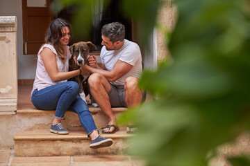 Happy couple sitting on stairs with dog