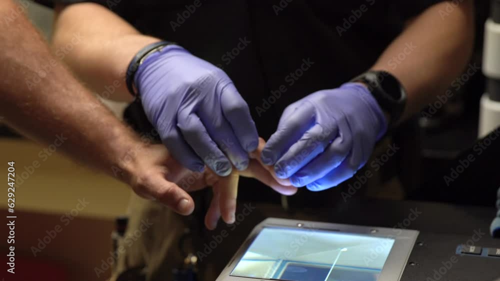 Poster security man with gloves taking fingerprints of a person on a scanning device
