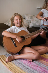 Happy child playing acoustic guitar at home