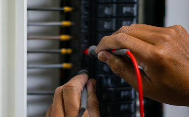Electrician work tester measuring voltage and current of power electric line in electrical cabinet control, Professional man uses tool commissioning test or checking circuit for protection system.