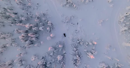 Fotobehang Aerial view above a snowmobile driving uphill a snowy fell, winter dusk in Lapland © Daniel Rönneberg/Wirestock Creators