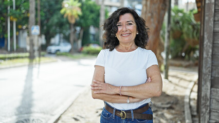 Fototapeta premium Middle age hispanic woman smiling confident standing with arms crossed gesture at park