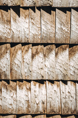 Wooden shingles. Natural roof material of rustic style. Abstract background. Brown and gray color. Old rooftop. Wall facade in village style. Wood pattern. Original surface plank cover