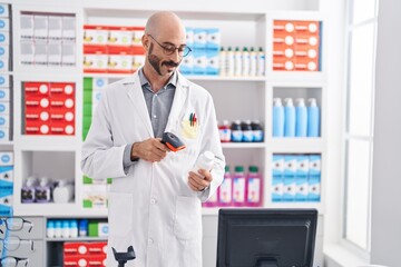 Naklejka na ściany i meble Young hispanic man pharmacist scanning pills bottle at pharmacy
