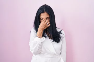 Foto op Plexiglas Mature hispanic woman standing over pink background tired rubbing nose and eyes feeling fatigue and headache. stress and frustration concept. © Krakenimages.com