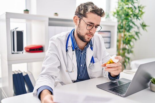 Young man doctor reading medical report holding pills at clinic