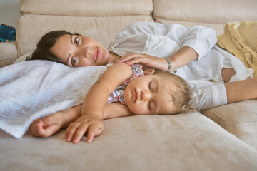 Mother with baby lying on sofa at home