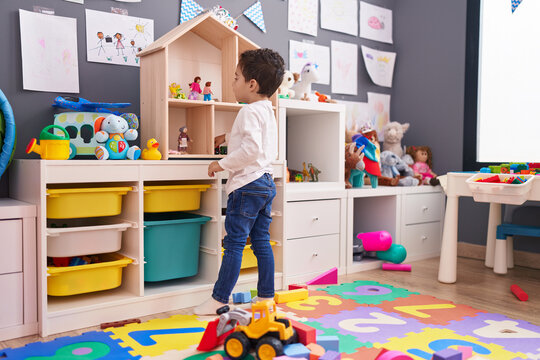 Adorable Hispanic Boy Standing On Back View Playing At Kindergarten