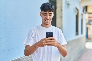 Fototapeta na wymiar Young hispanic man smiling confident using smartphone at street