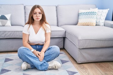 Young caucasian woman sitting on the floor at the living room depressed and worry for distress, crying angry and afraid. sad expression.