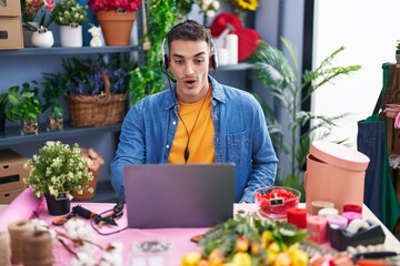 Handsome hispanic man working at florist shop doing video call scared and amazed with open mouth for surprise, disbelief face